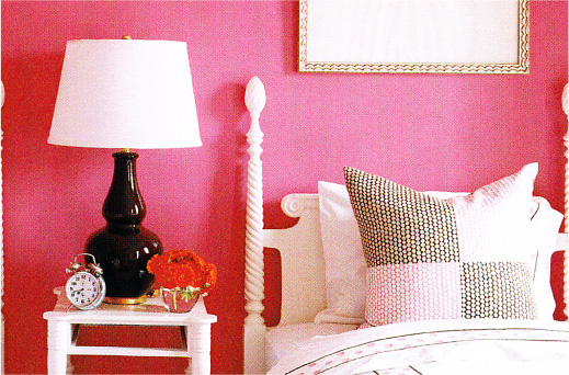 Close-up of a bed and nightstand in a raspberry pink bedroom.